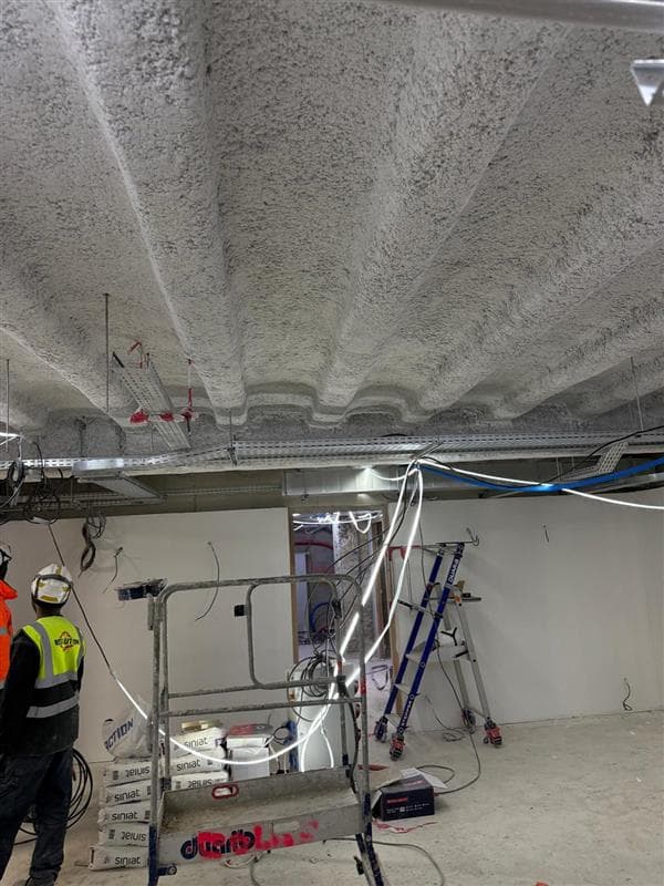 Chantier CSI Isolation en cours avec application de flocage coupe-feu Fibrofeu de Projiso sur la structure du plafond.